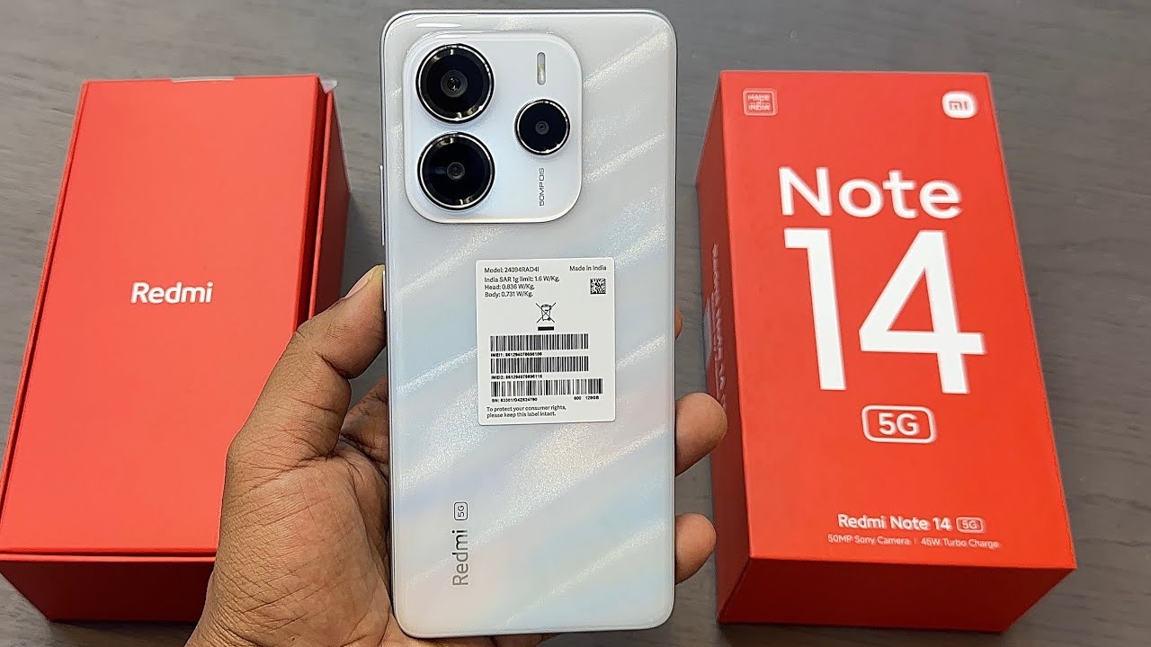 A silver Redmi Note 14 5G held beside its red retail packaging