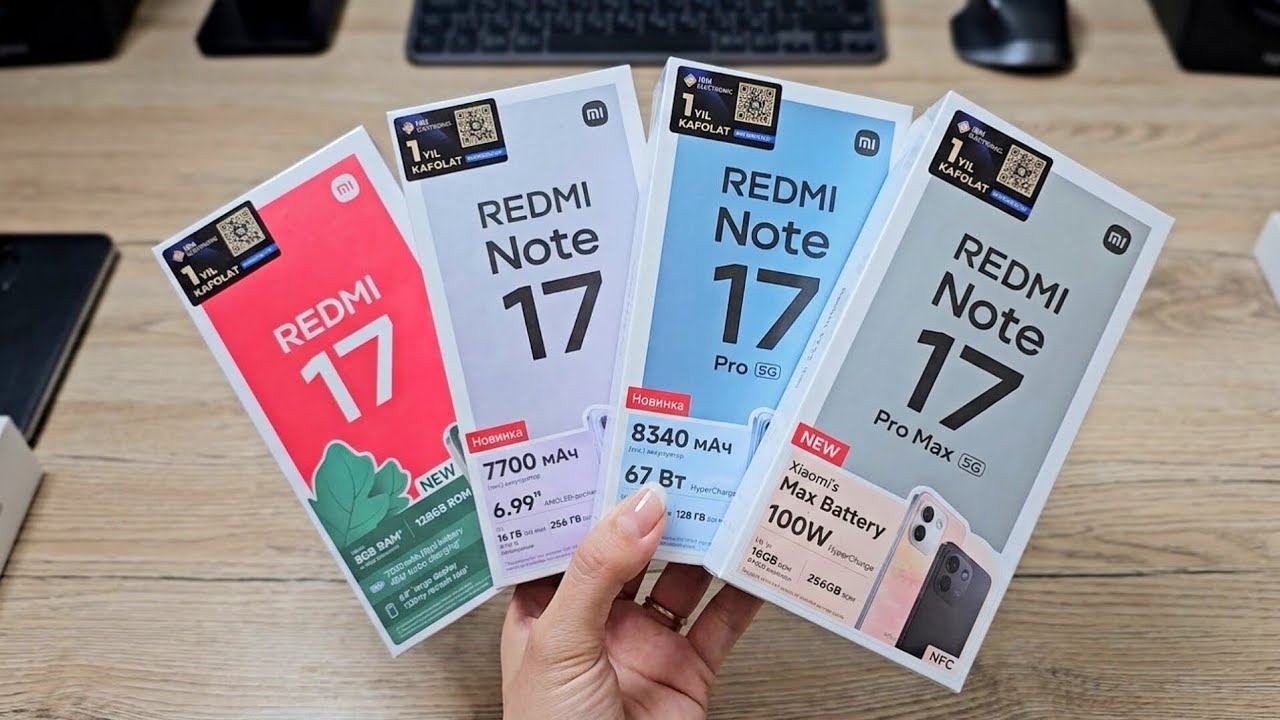 A hand holding four Redmi retail boxes, including Note 17 models, above a desk