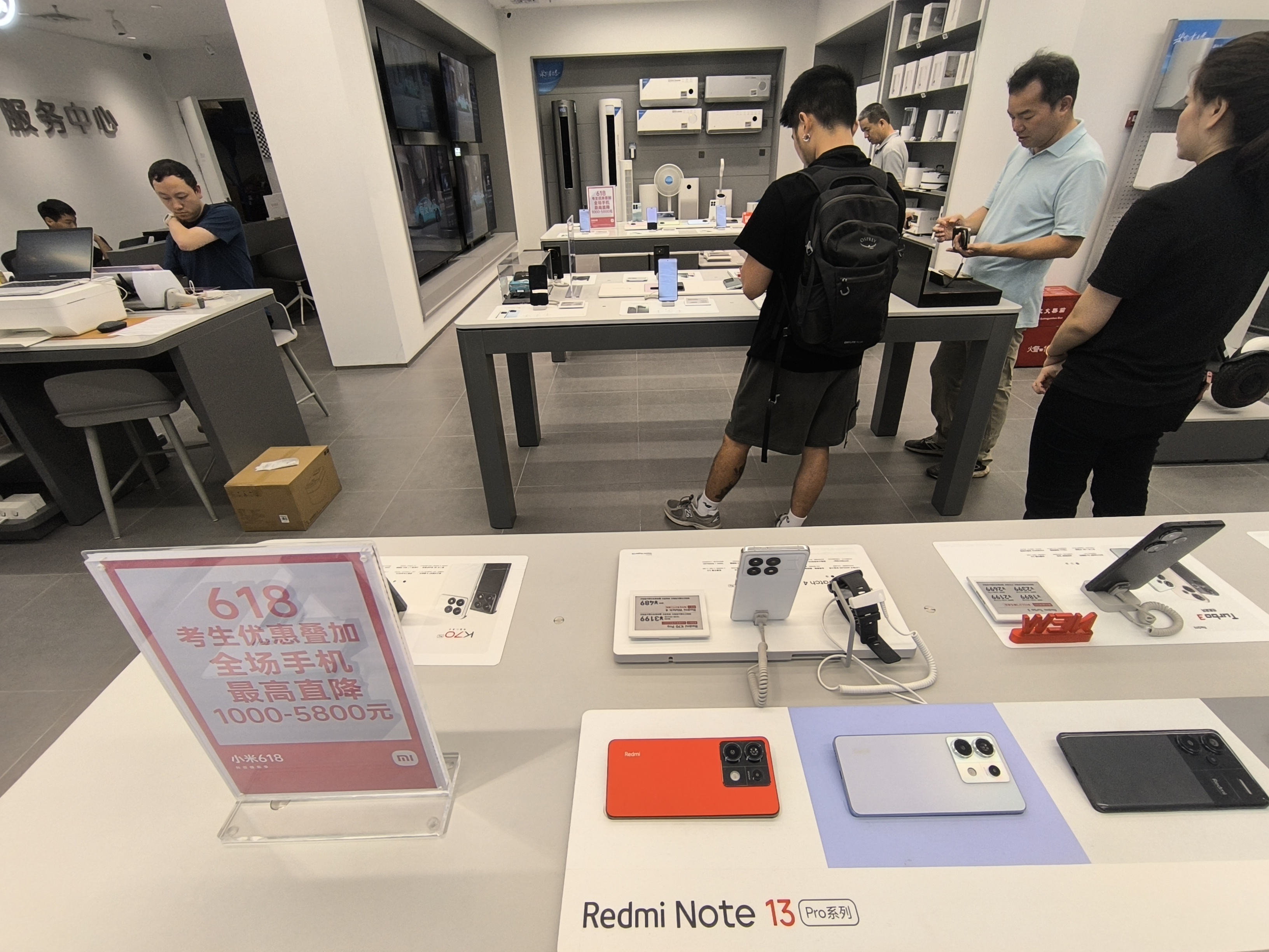 Redmi phones on display with televisions and home appliances inside a Xiaomi store
